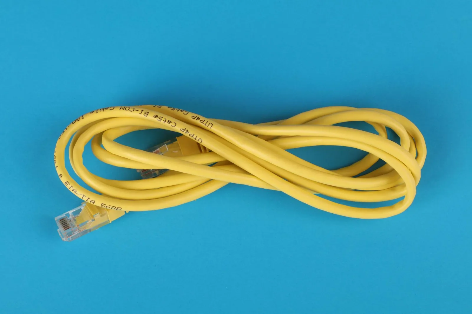A coiled yellow Cat5e ethernet cable with RJ45 connectors on a blue background